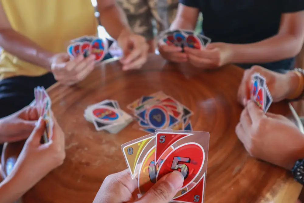 People sitting around a table and getting to play Uno.