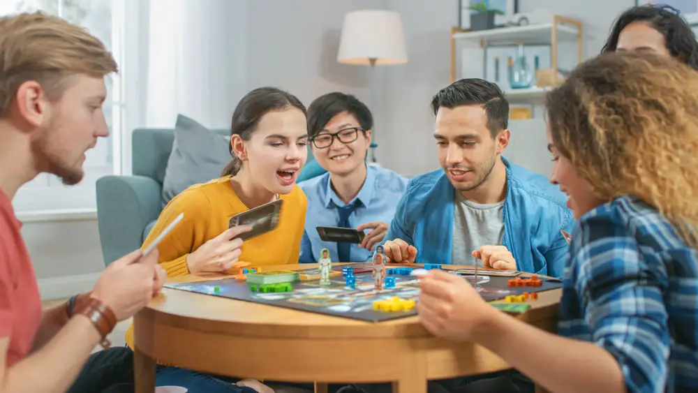 People gathered around a table playing a board game that may or may not have a theme.