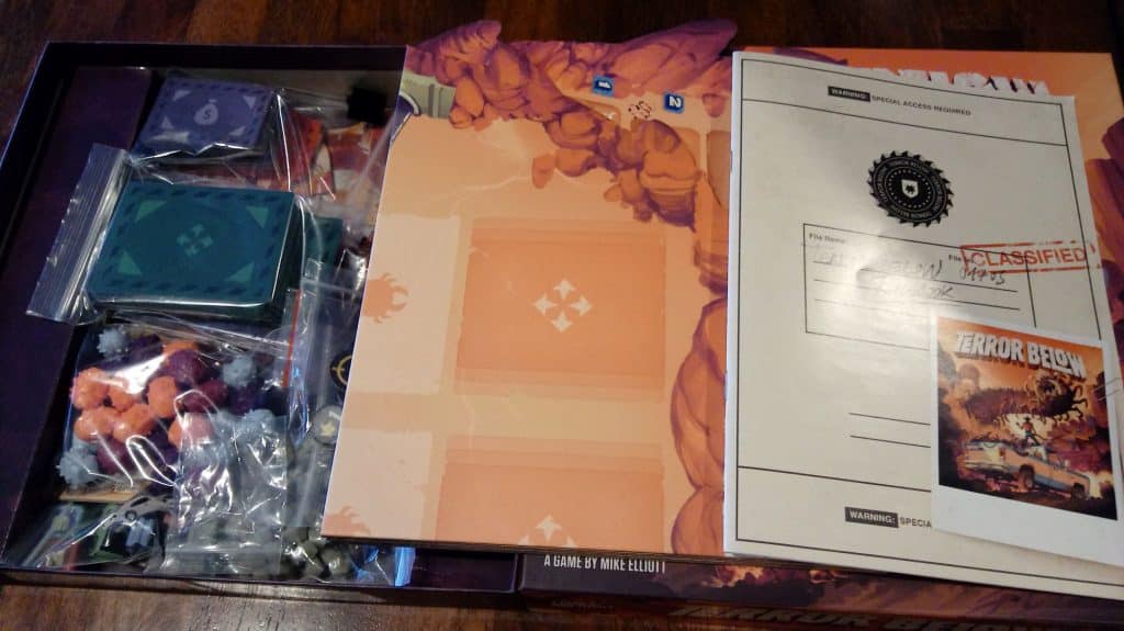 Closeup of opened Terror Below box, which is showing some of the game components.
