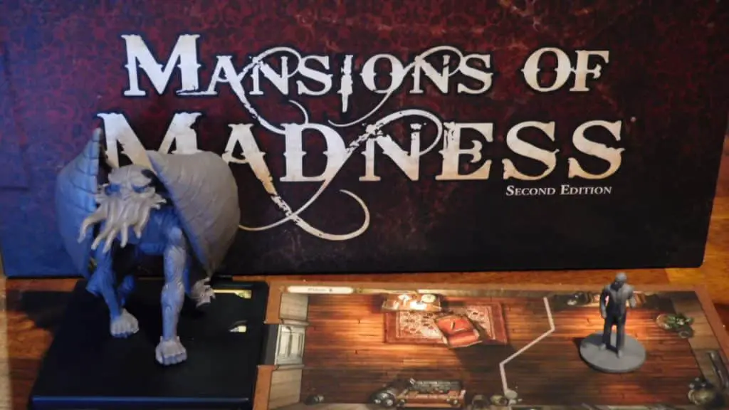 A closeup showing the box of Mansions Of Madness 2nd Edition along with two miniatures and a room tile.