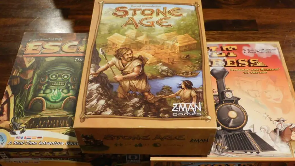 Some games on a table, including Stone Age, Colt Express, and Escape: The Curse Of The Temple.
