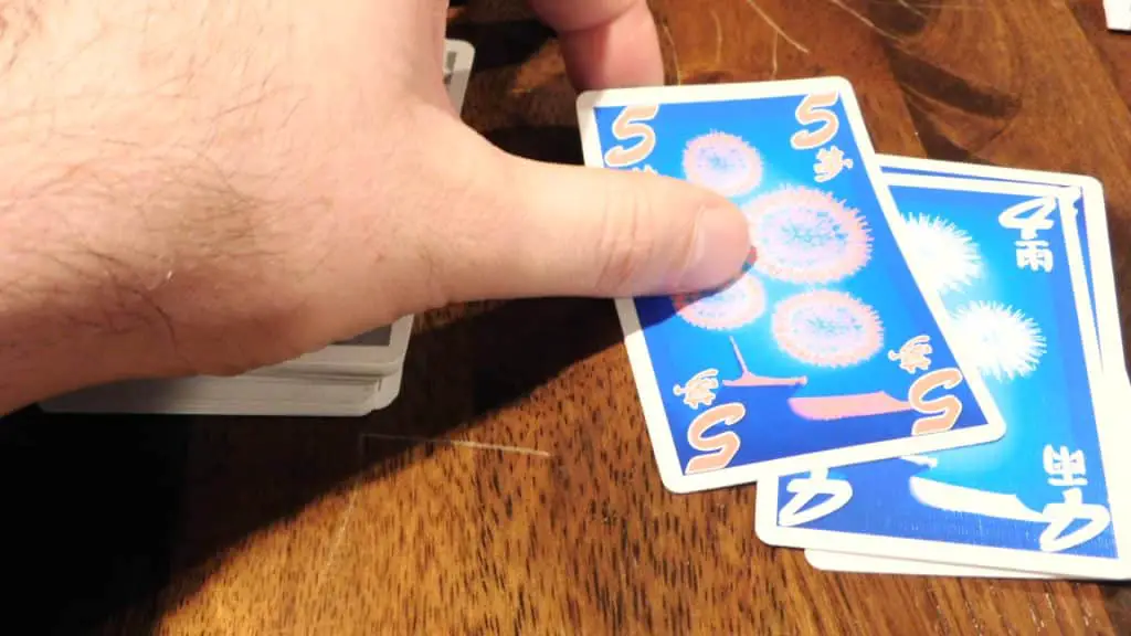 A hand discarding a card in Hanabi.