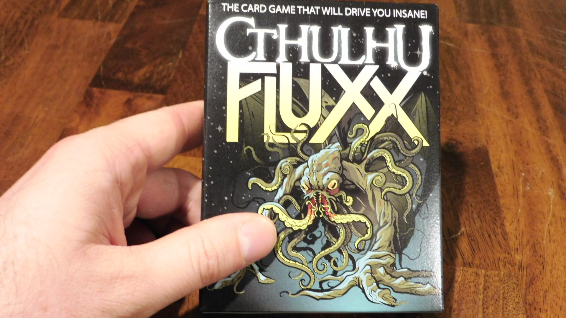 A hand holding the Cthulhu Fluxx box.