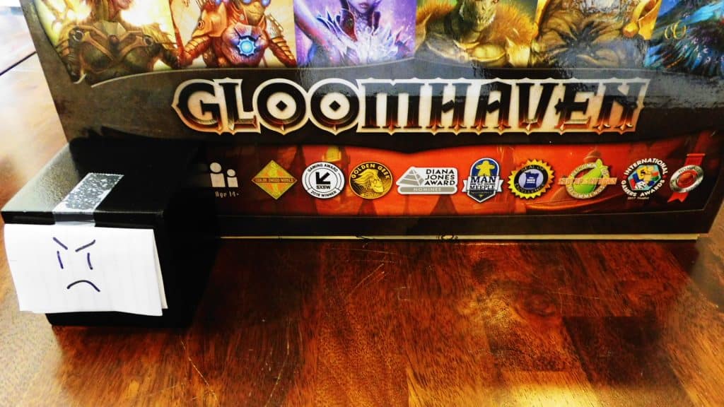 A closeup of Alpha Gamer Al and one side of the game box for Gloomhaven.