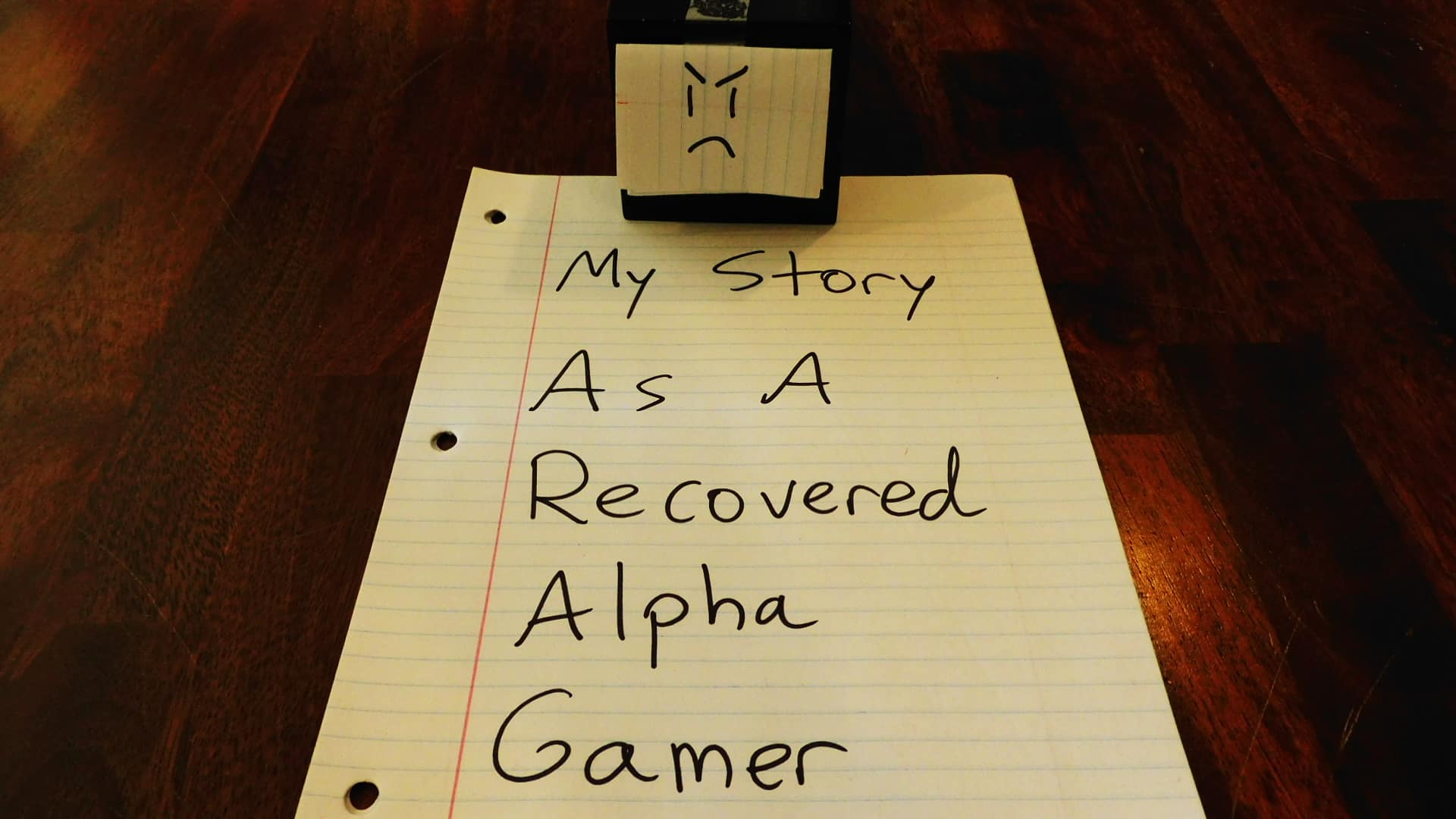 Alpha Gamer Al sitting on a piece of paper saying, "My Story As A Recovered Alpha Gamer."