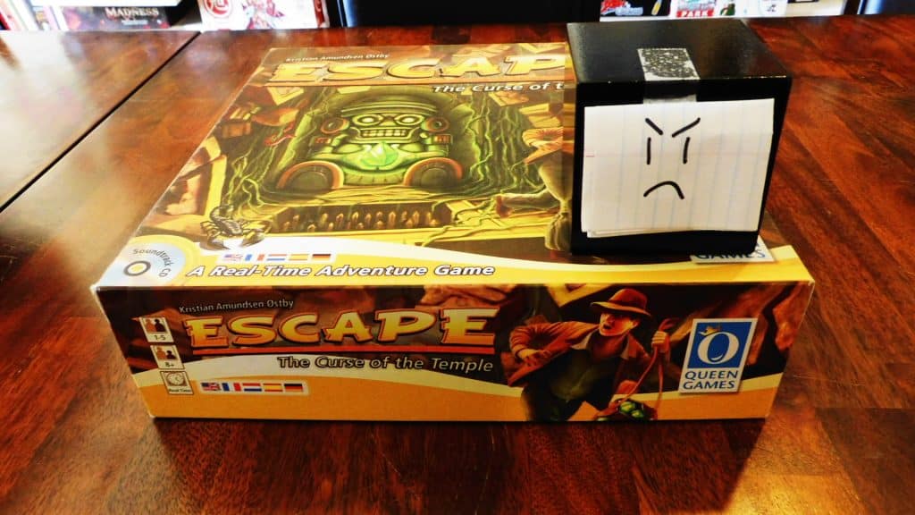Alpha Gamer Al sitting on top of the Escape: The Curse Of The Temple board game box.