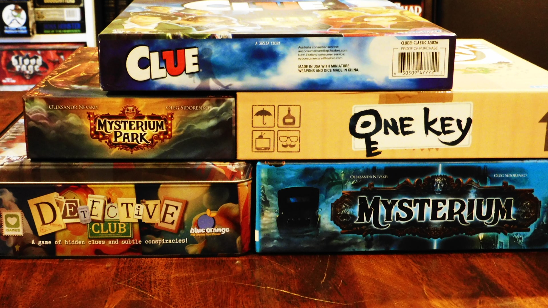 The sides of the game boxes for Mysterium, Clue, One Key, Mysterium Park, and Detective Club.